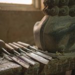Illustration: chisels and a mallet on a workbench beside a half-finished carved stone lion