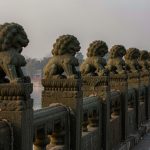 Illustration: a row of weathered carved stone lions along the balustrade of an old stone bridge