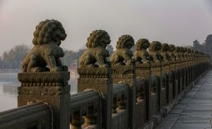 Illustration: a row of weathered carved stone lions along the balustrade of an old stone bridge